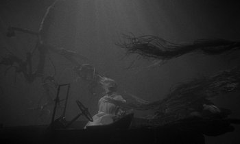 Movie still from “The Night of the Hunter” (1955), directed by Charles Laughton – A black and white photo of a woman sitting in a chair; Wide shot, Low angle