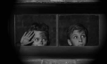 Movie still from “The Night of the Hunter” (1955), directed by Charles Laughton – Two young men looking out a window at the camera; Close Up shot, High angle
