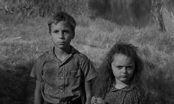 Movie still from “The Night of the Hunter” (1955), directed by Charles Laughton – A boy and a little girl standing next to each other; Medium shot, High angle