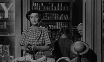 Movie still from “The Night of the Hunter” (1955), directed by Charles Laughton – An older woman holding a basket in front of a man and a girl; Medium shot, Over the shoulder angle
