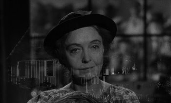 Movie still from “The Night of the Hunter” (1955), directed by Charles Laughton – An older woman wearing a hat and looking at the camera; Close Up shot, Over the shoulder angle