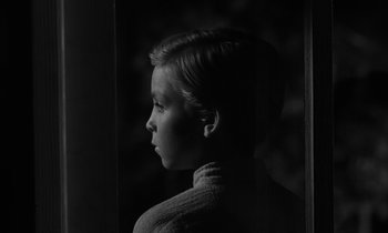 Movie still from “The Night of the Hunter” (1955), directed by Charles Laughton – A black and white photo of a young boy looking out a window; Close Up shot, Low angle