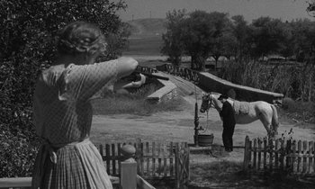 Movie still from “The Night of the Hunter” (1955), directed by Charles Laughton – An old photo of a man and a woman shooting guns; Wide shot, Over the shoulder angle