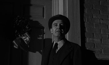 Movie still from “The Night of the Hunter” (1955), directed by Charles Laughton – A black and white photo of a man wearing a suit and hat; Medium shot, Low angle