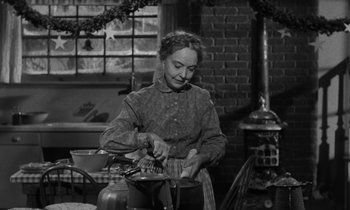 Movie still from “The Night of the Hunter” (1955), directed by Charles Laughton – An old photo of a woman in a kitchen preparing a meal; Medium shot, High angle