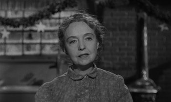 Movie still from “The Night of the Hunter” (1955), directed by Charles Laughton – An older woman is standing in front of a brick wall; Close Up shot, Over the shoulder angle