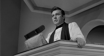 Movie still from “The Night of the Iguana” (1964), directed by John Huston – A man standing at the top of a stage with a microphone; Close Up shot, Low angle