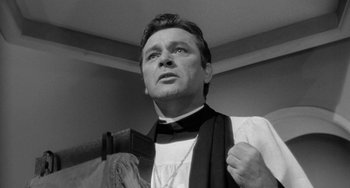 Movie still from “The Night of the Iguana” (1964), directed by John Huston – A black and white photo of a man in a priest's outfit; Close Up shot, Low angle