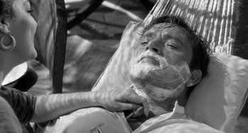 Movie still from “The Night of the Iguana” (1964), directed by John Huston – A man shaves his face while sitting in a chair; Close Up shot, High angle