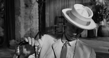 Movie still from “The Night of the Iguana” (1964), directed by John Huston – An older man wearing a white hat and holding a cane; Close Up shot, Over the shoulder angle
