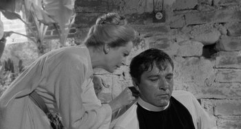 Movie still from “The Night of the Iguana” (1964), directed by John Huston – A man getting his hair cut by a woman in front of a brick wall; Close Up shot, Over the shoulder angle