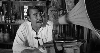 Movie still from “The Night of the Iguana” (1964), directed by John Huston – An old photo of a man with a pipe in his mouth; Medium shot, Low angle