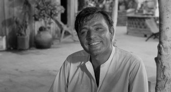 Movie still from “The Night of the Iguana” (1964), directed by John Huston – Black and white photograph of a man smiling for the camera; Close Up shot, Low angle