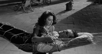 Movie still from “The Night of the Iguana” (1964), directed by John Huston – A man and a woman sitting in a hammock; Medium shot, High angle