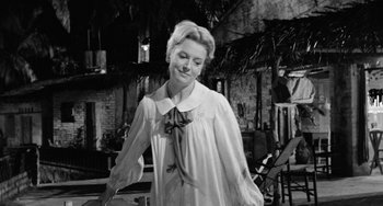Movie still from “The Night of the Iguana” (1964), directed by John Huston – An old photo of a woman wearing a white shirt and a bow tie; Medium shot, Low angle