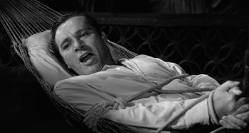Movie still from “The Night of the Iguana” (1964), directed by John Huston – A black and white photo of a man in a hammock; Close Up shot, High angle