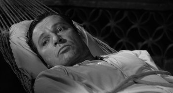 Movie still from “The Night of the Iguana” (1964), directed by John Huston – A black - and - white photo of a man laying in bed; Close Up shot, High angle