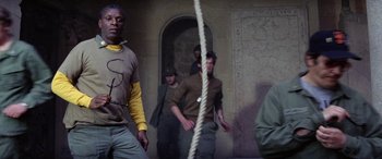 Movie still from “The Ninth Configuration” (1980), directed by William Peter Blatty – A group of people standing around a building; Medium shot, Low angle