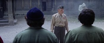 Movie still from “The Ninth Configuration” (1980), directed by William Peter Blatty – An old man in uniform standing in front of a group of people; Medium shot, Over the shoulder angle