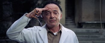 Movie still from “The Ninth Configuration” (1980), directed by William Peter Blatty – A man in a white lab coat holding a pair of scissors in his hand; Close Up shot, Low angle