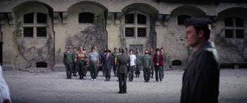 Movie still from “The Ninth Configuration” (1980), directed by William Peter Blatty – A group of men standing in front of a building; Extreme Wide shot, High angle