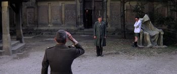 Movie still from “The Ninth Configuration” (1980), directed by William Peter Blatty – A man saluting another man wearing a trench coat; Wide shot, Over the shoulder angle