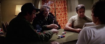 Movie still from “The Ninth Configuration” (1980), directed by William Peter Blatty – A group of people sitting at a table playing poker; Medium shot, Over the shoulder angle