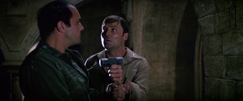Movie still from “The Ninth Configuration” (1980), directed by William Peter Blatty – A man holding a hammer in his hand while another man looks on; Close Up shot, Low angle