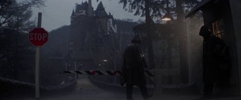 Movie still from “The Ninth Configuration” (1980), directed by William Peter Blatty – A man walking down the street in front of a castle; Wide shot, High angle