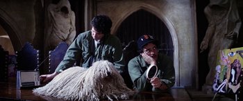 Movie still from “The Ninth Configuration” (1980), directed by William Peter Blatty – Two men sitting at a table next to a shaggy dog; Medium shot, Over the shoulder angle