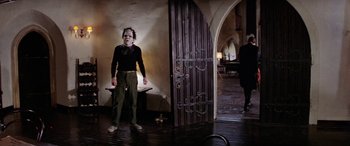 Movie still from “The Ninth Configuration” (1980), directed by William Peter Blatty – A man in a mask standing in front of an open door; Wide shot, Low angle