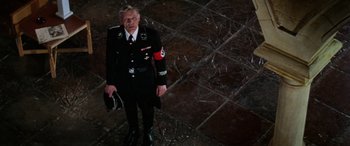 Movie still from “The Ninth Configuration” (1980), directed by William Peter Blatty – An older man in a uniform standing on a tiled floor; Wide shot, High angle