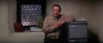 Movie still from “The Ninth Configuration” (1980), directed by William Peter Blatty – A man in a tan shirt and tie looking at his watch; Medium shot, Low angle