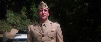 Movie still from “The Ninth Configuration” (1980), directed by William Peter Blatty – A man in a military uniform standing in front of trees; Close Up shot, Low angle