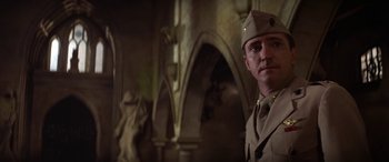 Movie still from “The Ninth Configuration” (1980), directed by William Peter Blatty – A man in a military uniform standing in front of statues; Medium shot, Low angle
