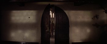 Movie still from “The Ninth Configuration” (1980), directed by William Peter Blatty – A man standing in a doorway of an old church; Wide shot, Low angle