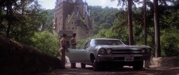 Movie still from “The Ninth Configuration” (1980), directed by William Peter Blatty – Two men standing next to a car in front of a castle; Wide shot, Low angle