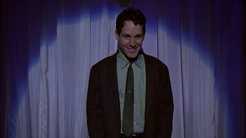 Movie still from “The Object of My Affection” (1998), directed by Nicholas Hytner – A man in a suit and tie smiling for the camera; Medium shot, Low angle