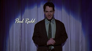 Movie still from “The Object of My Affection” (1998), directed by Nicholas Hytner – A man wearing a suit and tie standing in front of a curtain; Medium shot, Low angle