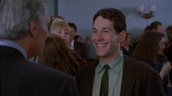 Movie still from “The Object of My Affection” (1998), directed by Nicholas Hytner – A man in a suit and tie smiling for the camera; Medium shot, Over the shoulder angle