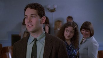 Movie still from “The Object of My Affection” (1998), directed by Nicholas Hytner – A man and a woman are standing in front of a crowd; Medium shot, Over the shoulder angle