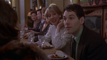 Movie still from “The Object of My Affection” (1998), directed by Nicholas Hytner – A group of people sitting at a table with plates of food on it; Medium shot, Over the shoulder angle