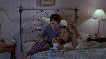 Movie still from “The Object of My Affection” (1998), directed by Nicholas Hytner – A man and a woman sitting on a bed playing nintendo wii; Medium shot, High angle