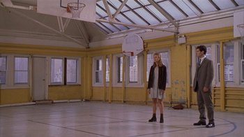 Movie still from “The Object of My Affection” (1998), directed by Nicholas Hytner – A woman standing in a gym holding a basketball hoop; Wide shot, Low angle