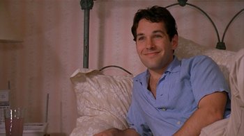 Movie still from “The Object of My Affection” (1998), directed by Nicholas Hytner – A man sitting on top of a bed next to a pillow; Close Up shot, Low angle