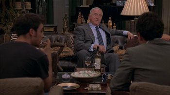 Movie still from “The Object of My Affection” (1998), directed by Nicholas Hytner – An older man sitting on a couch in front of a group of people; Medium shot, Over the shoulder angle