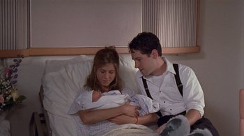 Movie still from “The Object of My Affection” (1998), directed by Nicholas Hytner – A man and a woman holding a baby in a hospital bed; Medium shot, High angle