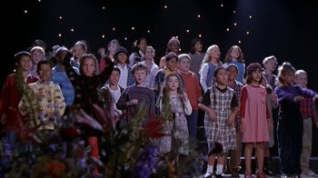 Movie still from “The Object of My Affection” (1998), directed by Nicholas Hytner – A large group of children standing in front of a stage; Wide shot, High angle