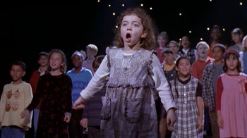 Movie still from “The Object of My Affection” (1998), directed by Nicholas Hytner – A group of children singing in front of an audience; Medium shot, High angle