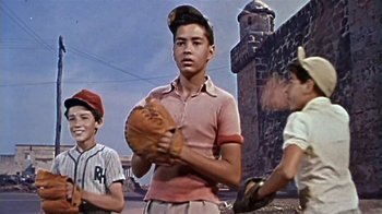Movie still from “The Old Man and the Sea” (1958), directed by Fred Zinnemann – A young man holding a baseball mitt in front of two other young men; Medium shot, Low angle
